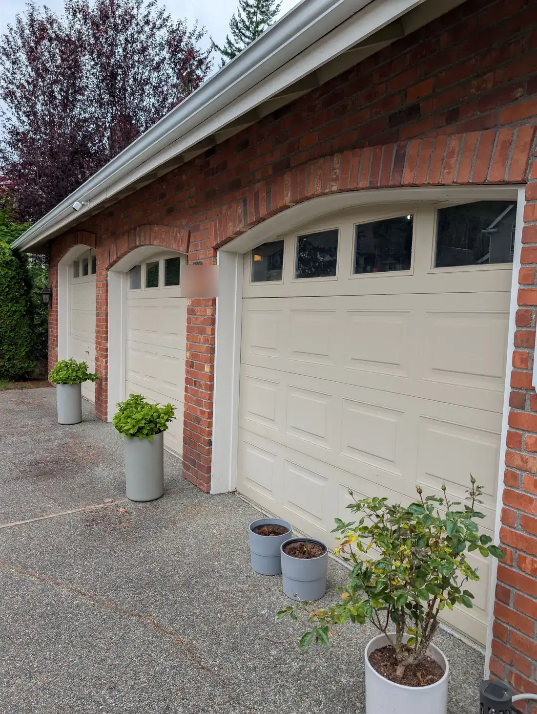Bellevue brick home with faded cream garage doors before replacement