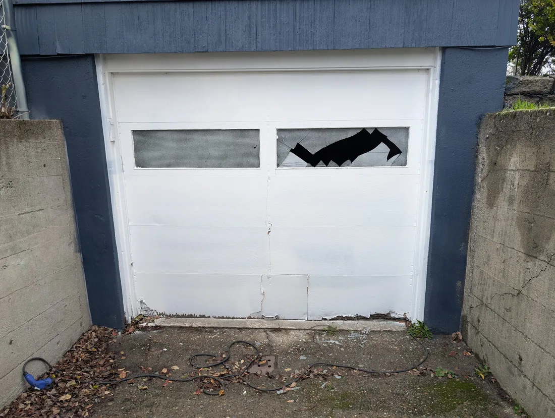Tukwila garage door with a smashed window and rusted bottom panel before replacement